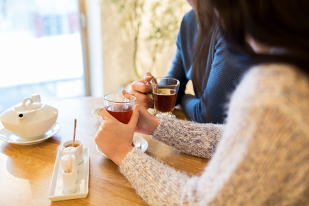 people, drinks and dating concept - close up of couple drinking tea at cafeの写真素材