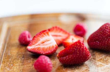 fruits, berries, diet, eco food and objects concept - close up of fresh ripe red strawberries on cutting boardの写真素材