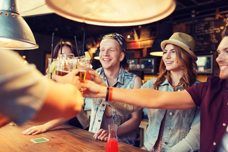 people, leisure, celebration and party concept - group of happy smiling friends clinking glasses...