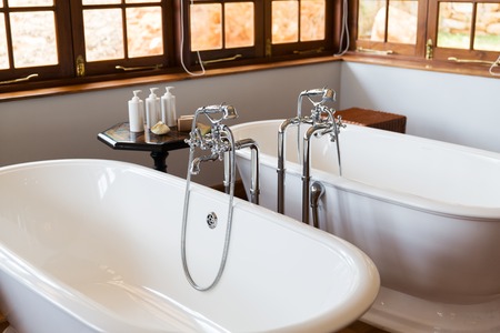 sanitary, plumbing and washing concept - close up of bathroom with two bathtubs