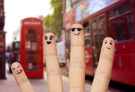 travel, tourism, family, people and body parts concept - close up of four fingers with smiley faces over london city street and red bus backgroundの写真素材