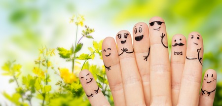gesture, family, people and body parts concept - close up of two hands showing fingers with smiley faces over natural green herbal backgroundの写真素材