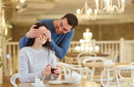people, surprise and dating concept - happy couple drinking tea at cafe or restaurantの写真素材