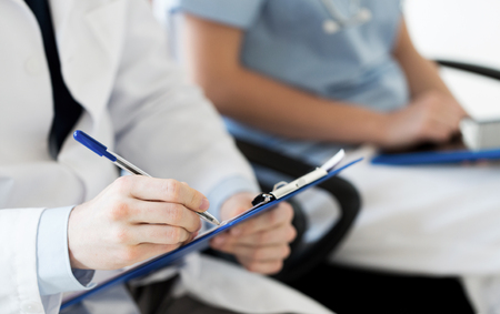 education, profession, people and medicine concept - close up of happy doctors with clipboard at seminar or hospitalの写真素材