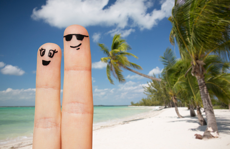 family, travel, summer holidays, tourism and body parts concept - close up of two fingers with smiley faces over exotic tropical beach with palm trees backgroundの写真素材