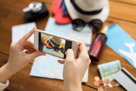 vacation, tourism, travel, technology and people concept - close up of woman with smartphone photographing map and travel stuffの写真素材