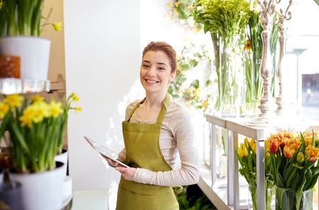 people, business, technology, sale and floristry and concept - happy smiling florist woman with tablet pc computer at flower shopの写真素材