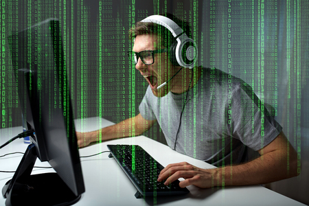 technology, gaming, entertainment, let's play and people concept - angry screaming young man in headset with pc computer playing game at home and streaming playthrough or walkthrough videoの写真素材