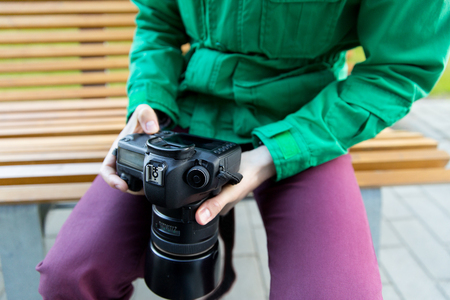 people, photography, technology, leisure and lifestyle - close up of male photographer with digital camera sitting on city street benchの写真素材