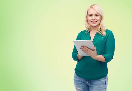 technology, internet and people concept concept - smiling woman with tablet pc computer over green natural backgroundの写真素材