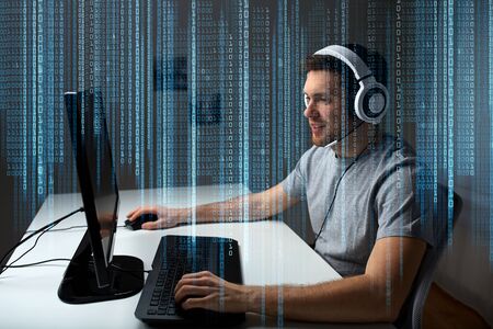 technology, gaming, entertainment, let's play and people concept - happy young man in headset with pc computer playing game at home and streaming playthrough or walkthrough videoの写真素材