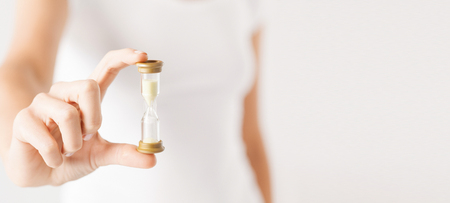 close up of woman hand holding hourglass.