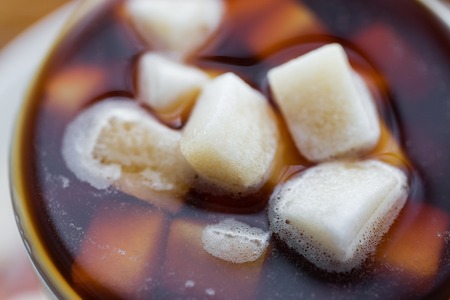close up of lump sugar heap drowned in cup of coffee or teaの写真素材