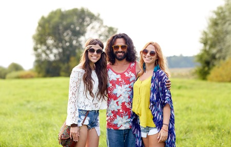 nature, summer, youth culture and people concept - smiling young hippie friends in sunglasses on green fieldの写真素材