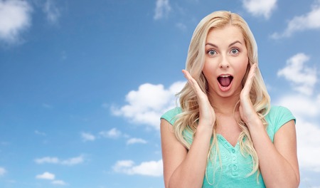 emotions, expressions and people concept - surprised smiling young woman or teenage girl over blue...