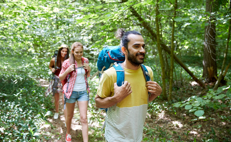 adventure, travel, tourism, hike and people concept - group of smiling friends walking with...