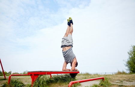 fitness, sport, training and lifestyle concept - young man exercising on bench outdoorsの写真素材