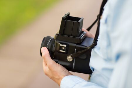 people, photography, technology, leisure and lifestyle - close up of male photographer with digital camera on city streetの写真素材