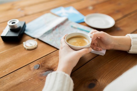 vacation, tourism, travel, destination and people concept - close up of hands with coffee cup and...