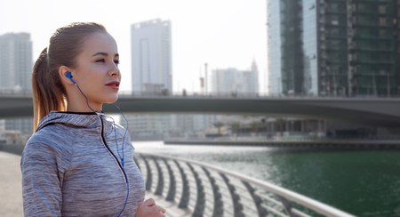 fitness, sport, people, technology and lifestyle concept - happy woman running and listening to...