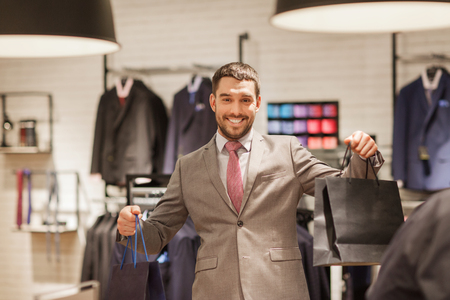 sale, fashion, retail, business style and people concept - happy man with shopping bags at clothing storeの写真素材