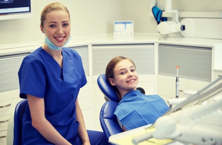 people, medicine, stomatology and health care concept - happy female dentist with patient girl at dental clinic officeの写真素材