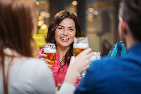 leisure, eating, food and drinks, people and holidays concept - smiling friends having dinner and drinking beer at restaurant or pubの写真素材