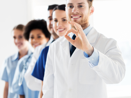 gesture, education, people, health care and medicine concept - group of happy doctors showing ok hand sign at hospitalの写真素材