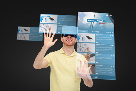 3d technology, virtual reality, internet, mass media and people concept - happy young man in virtual reality headset or 3d glasses playing game over black background with world news on screensの写真素材