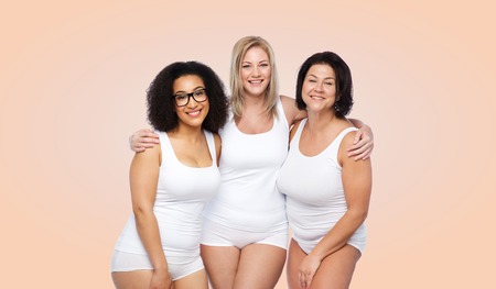 friendship, beauty, body positive and people concept - group of happy plus size women in white underwear over beige backgroundの写真素材