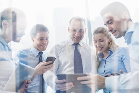 business, teamwork, people and technology concept - business team with tablet pc and smartphones meeting in officeの写真素材