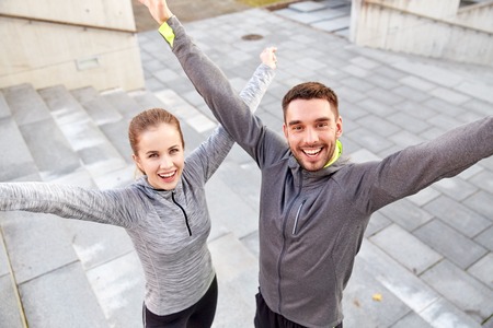 fitness, sport, people and lifestyle concept - happy smiling couple outdoors on city streetの写真素材