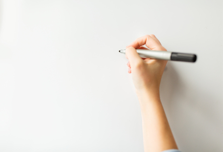 office, business, people and education concept - close up of hand with marker writing or drawing something on white board or wallの写真素材
