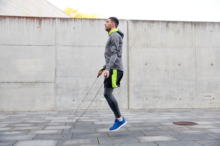 fitness, sport, people, exercising and lifestyle concept - man skipping with jump rope outdoorsの写真素材