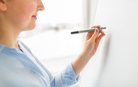 office, business, people and education concept - close up of woman with marker writing or drawing something on white boardの写真素材