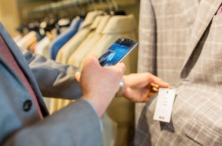 sale, shopping, fashion, technology and people concept - close up of man in suit with smartphone...