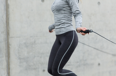 fitness, sport, people, exercising and lifestyle concept - close up of woman skipping with jump rope outdoorsの写真素材