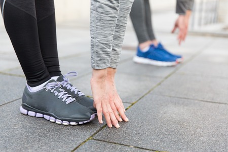 fitness, sport, exercising, training and people concept - close up of couple stretching on city...