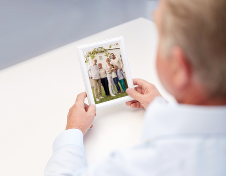 oldness, memories, nostalgia and people concept - close up of old man holding and looking at happy family photoの写真素材