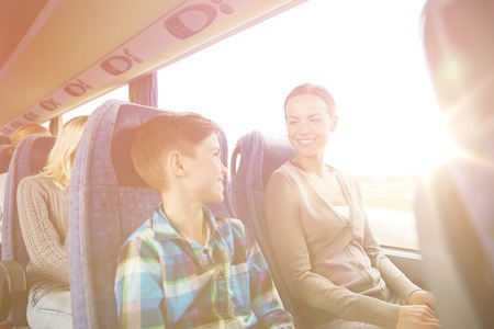 travel, tourism, family, technology and people concept - happy mother and son riding in travel bus