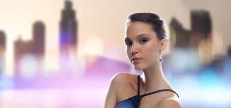 beauty, jewelry, people and luxury concept - beautiful young asian woman with earring over city...