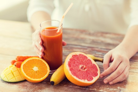 healthy eating, food, dieting and people concept - close up of woman hands with fruits and fresh juice sitting at tableの写真素材