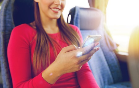 transport, tourism, road trip and people concept - close up of woman in travel bus texting or...