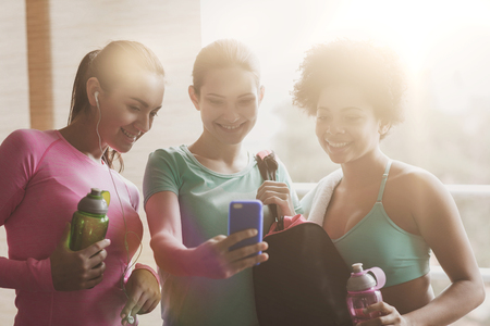 fitness, sport, training, gym and lifestyle concept - group of happy women with bottles and smartphone in gymの写真素材