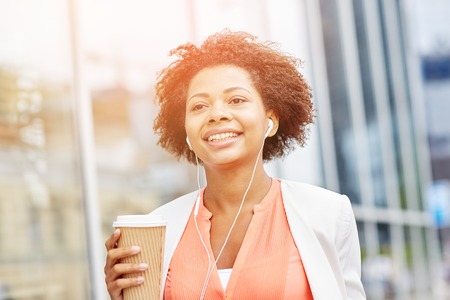 business and people concept - young smiling african american businesswoman with coffee cup in cityの写真素材