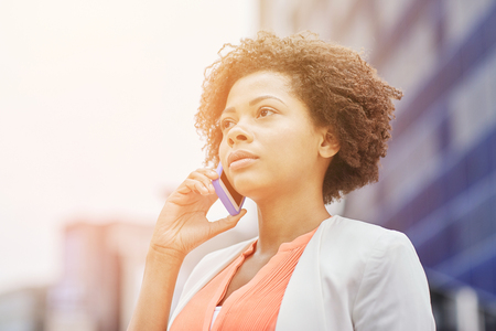 business, communication, technology and people concept - young african american businesswoman calling on smartphone in cityの写真素材