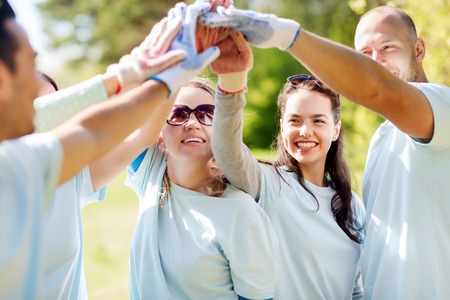 volunteering, charity, people, gesture and ecology concept - group of happy volunteers making high...