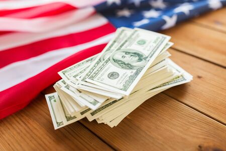 budget, finance and nationalism concept - close up of american flag and dollar cash money on woodの写真素材
