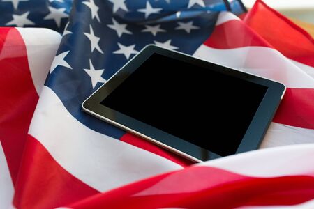 technology, american independence day, patriotism and nationalism concept - close up of tablet pc computer on american flagの写真素材