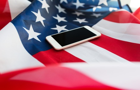 technology, american independence day, patriotism and nationalism concept - close up of smartphone computer on american flagの写真素材